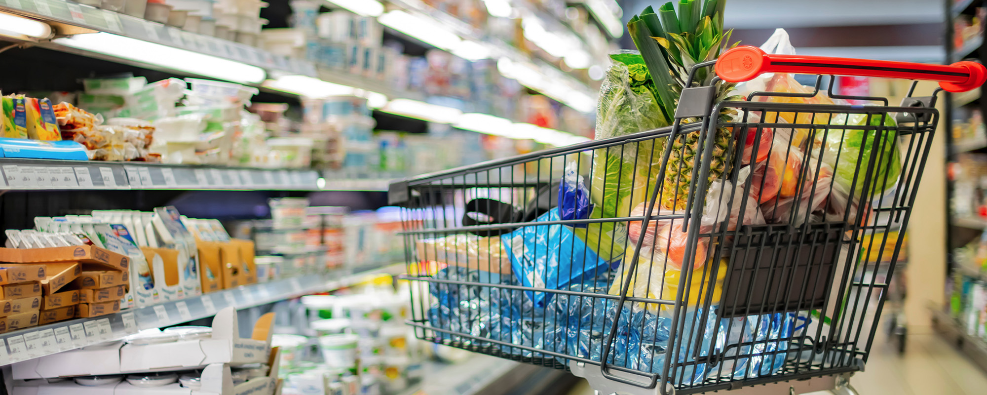 a shopping cart with grocery products in a supermarket