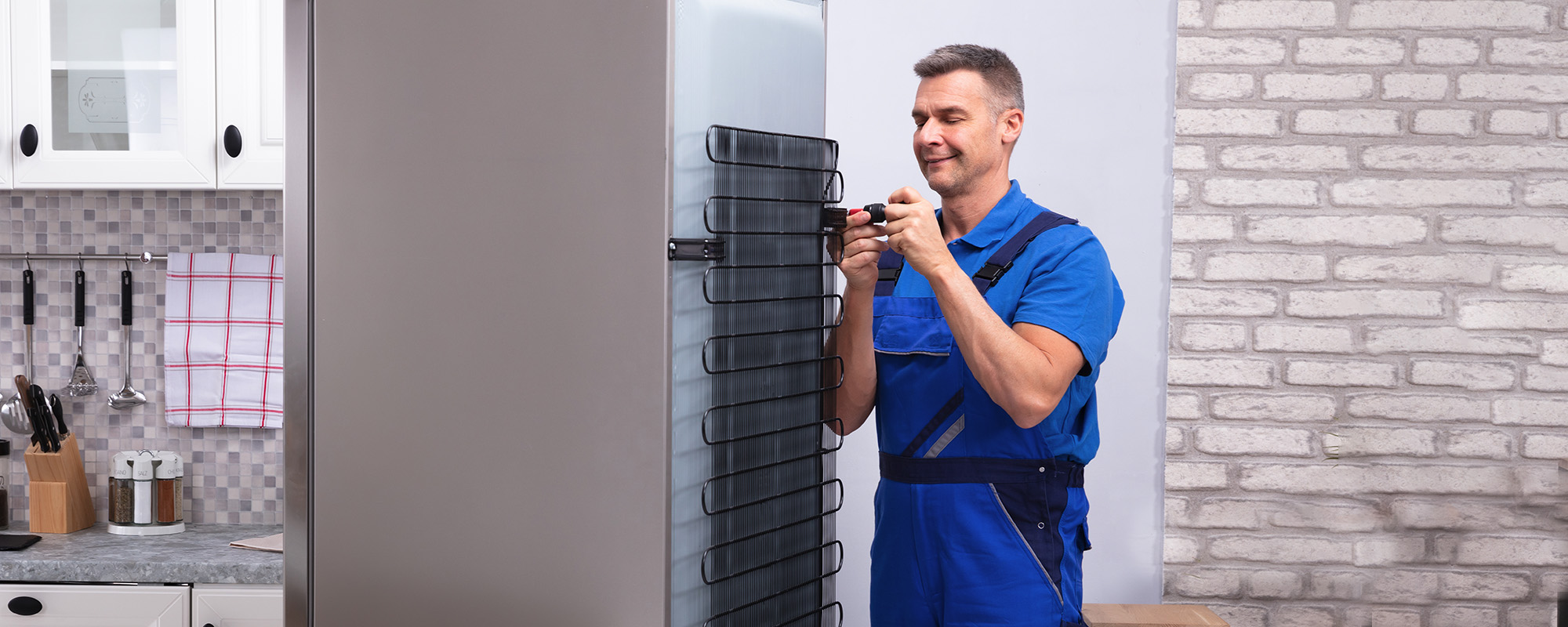 serviceman in overall working on fridge