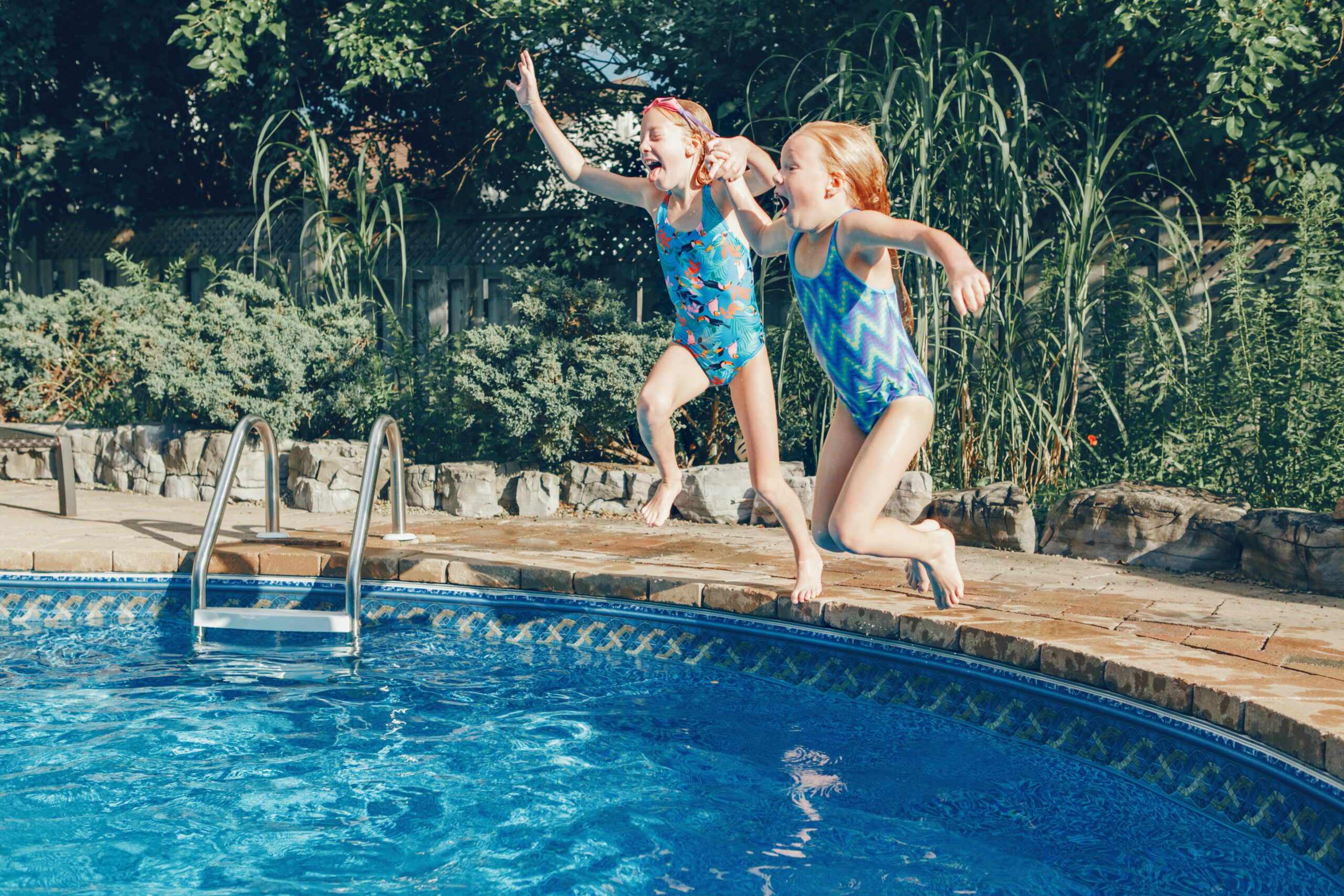 two kids jumping in a swimming pool