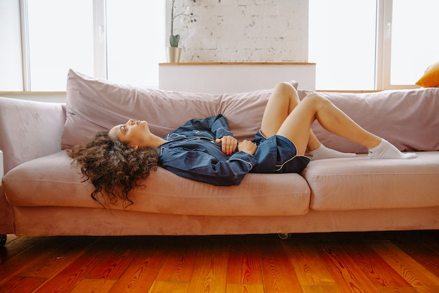 woman laying on couch suffering from stomach pain